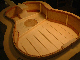 Santos may have been the first to stiffen up the treble side of the soundboard with this bracing design by angling the harmonic bar.  Note the straight braces which may tend to reveal the character of individual strings somewhat more than conventional angled braces.